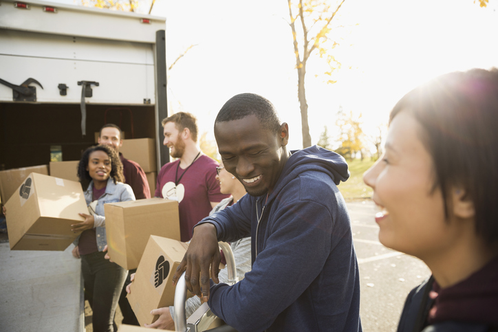 Smiling Volunteers Unloading Cardboard Boxes From Truck