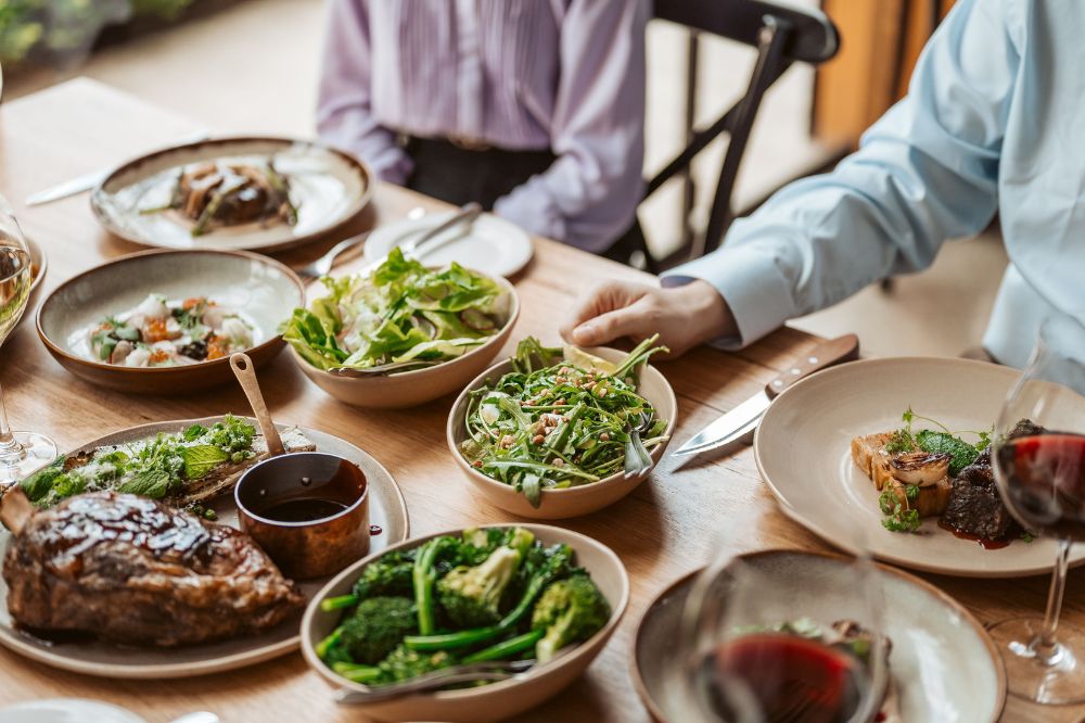 A table with plates of food and glasses of red wine.