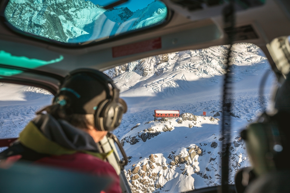 The view from a helicopter looking over a snowy mountain peak