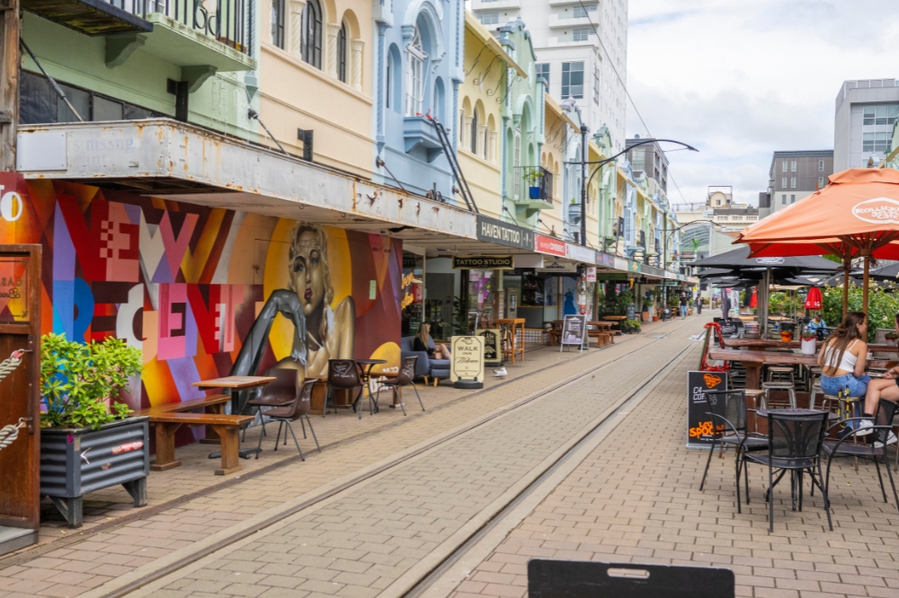 An urban laneway with colourful buildings and restaurants with people dining outside