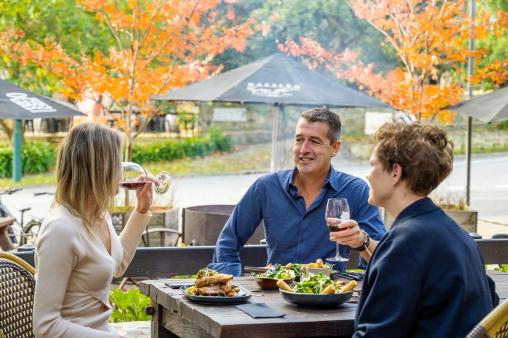 A group of people sit at a table with food and wine