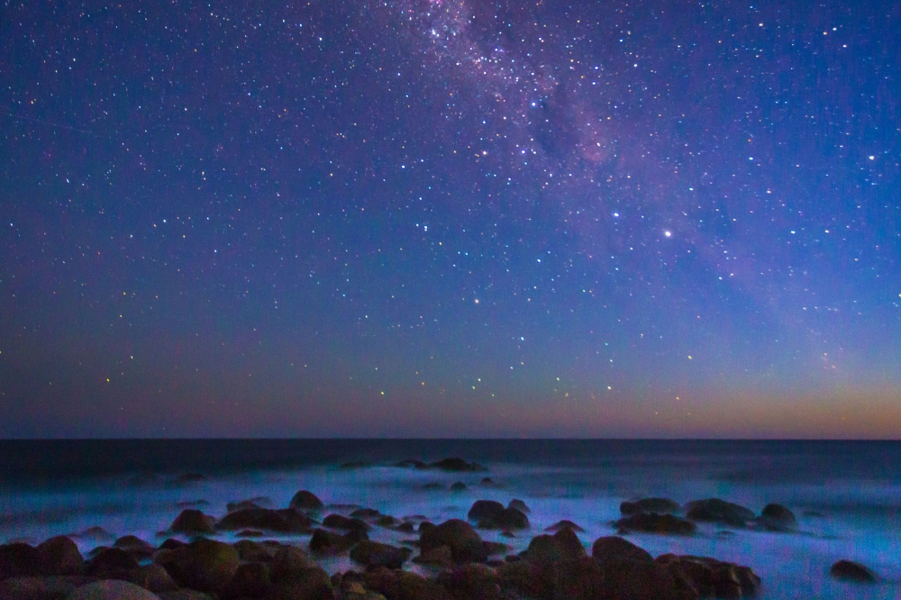 A starry night with Aurora Australis in the sky with deep purple tones