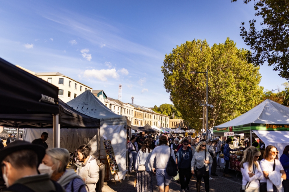 A bustling market with people walking through a large line of stalls
