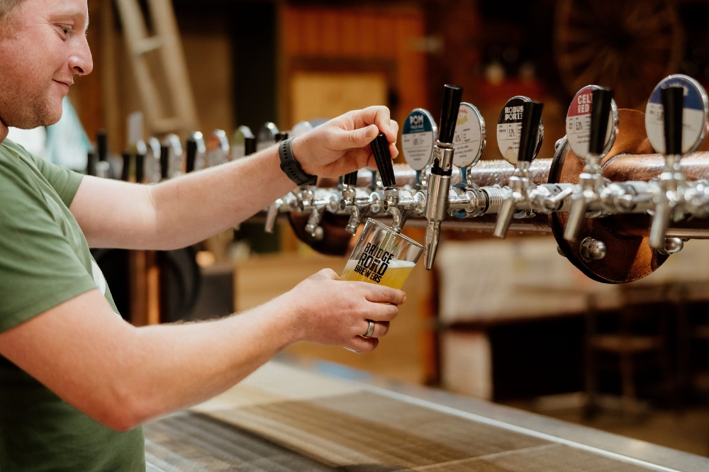 A man pours a beer into a glass out of a beer tap