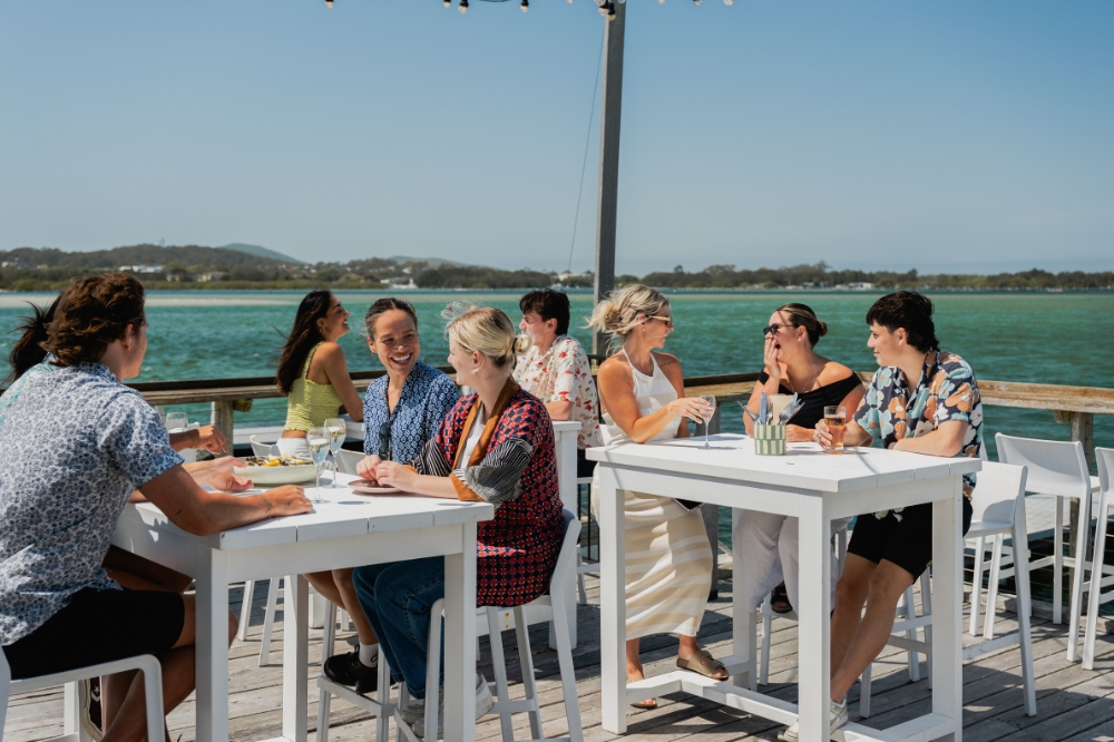Friends enjoying fresh Sydney Oysters by the lakeside at Thirty Three Degrees in Tuncurry