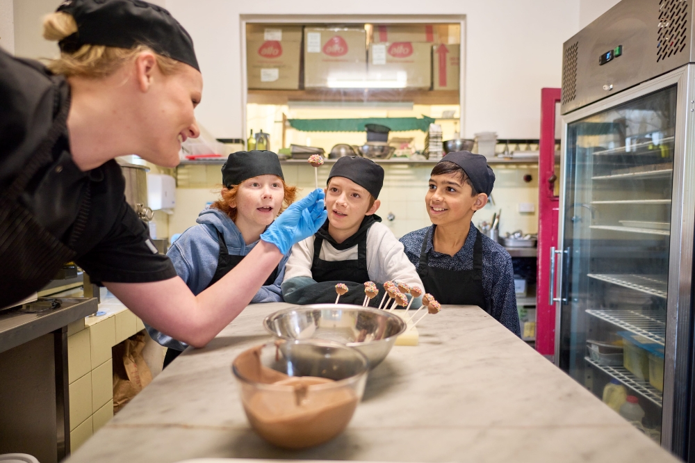 A person shows a group of kids a chocolate stick with sprinkles