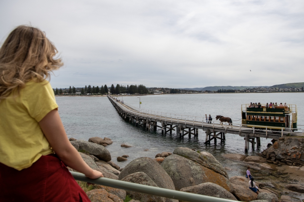 A child watches a horse drawn tram go along a jetty