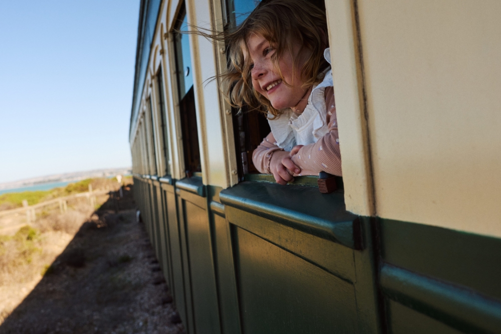 A child smiles looking out a train window