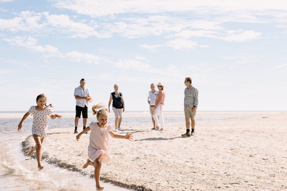 Kids run along the water at the beach