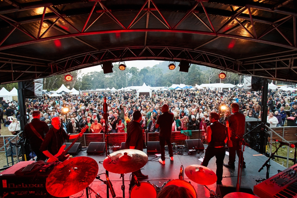 A band plays on a stage with a crowd watching