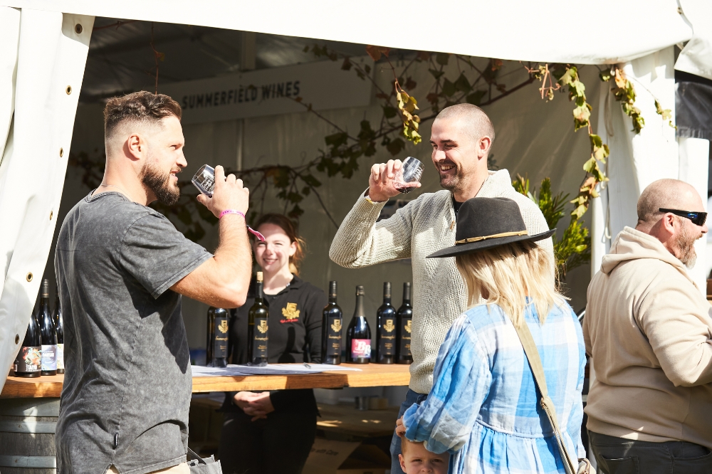 People stand tasting wine and smiling