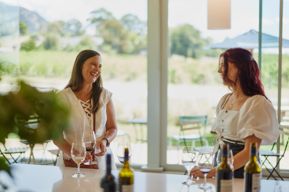 People smile at each other while they taste wine at a winery