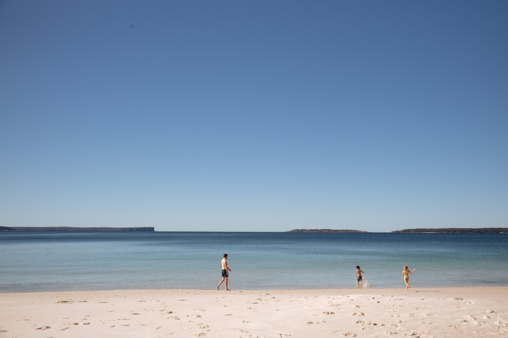 People run into the water at a quiet beach with white sand